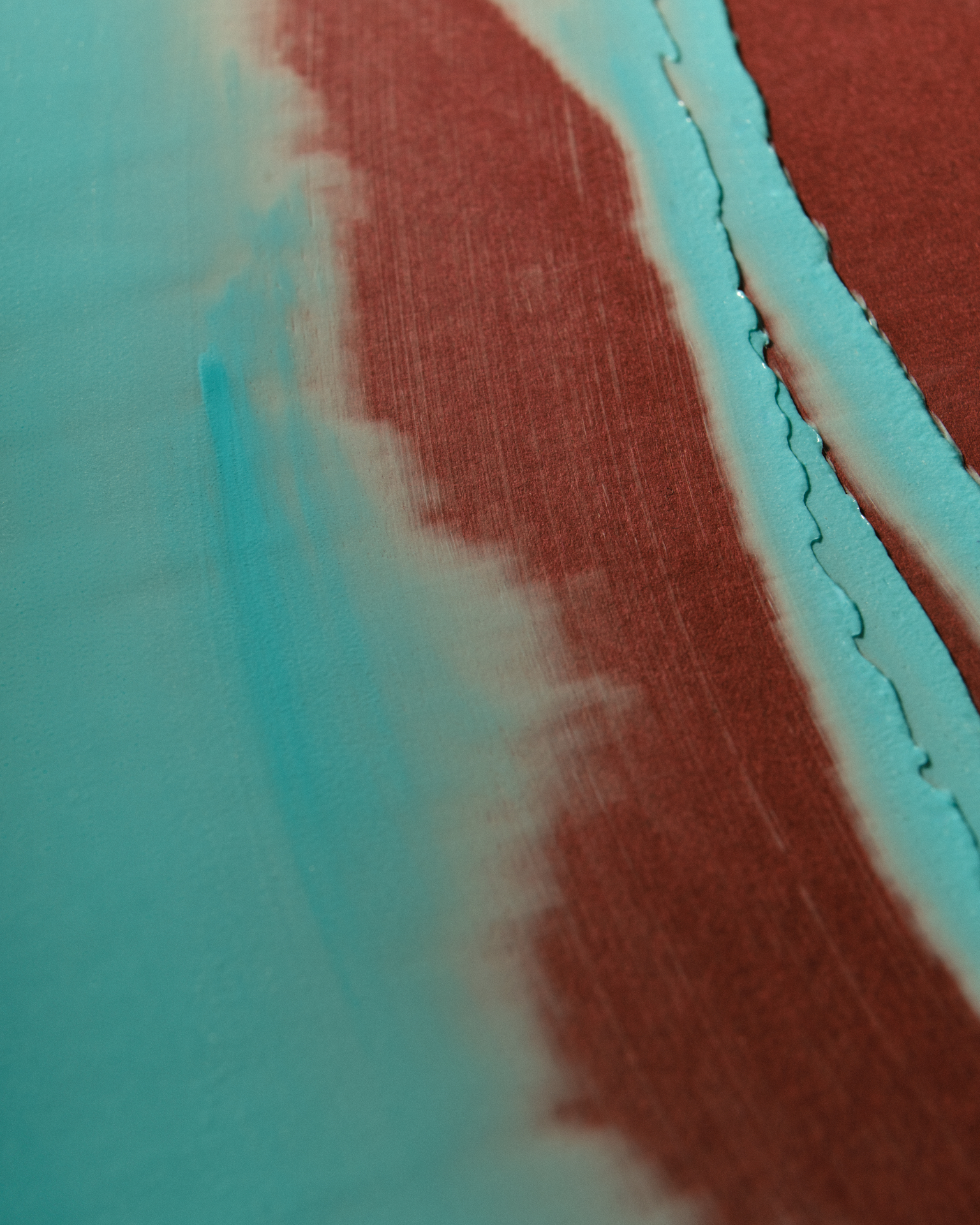 Texture cosmétique turquoise appliquée en larges mouvements laissant apparaître un fond brun sous-jacent.